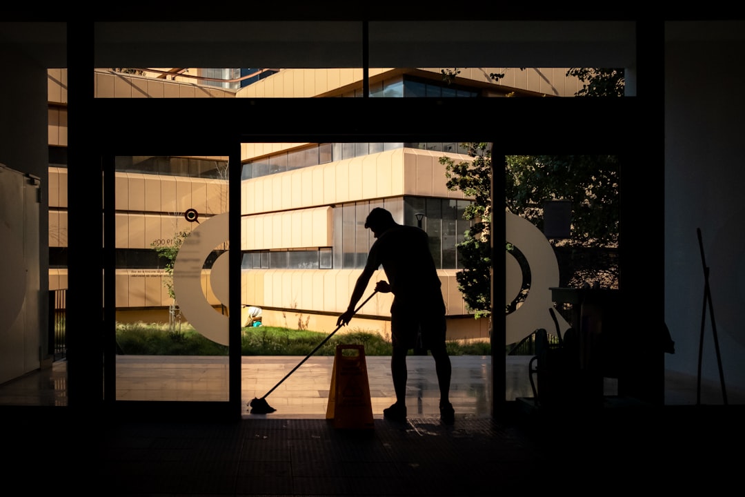 A man is cleaning the floor by an entrance door.